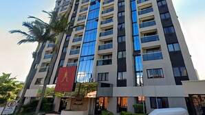 A high-rise building with multiple floors, large windows, and a prominent red flag. - Marsala Apart Hotel (Mogi das Cruzes)