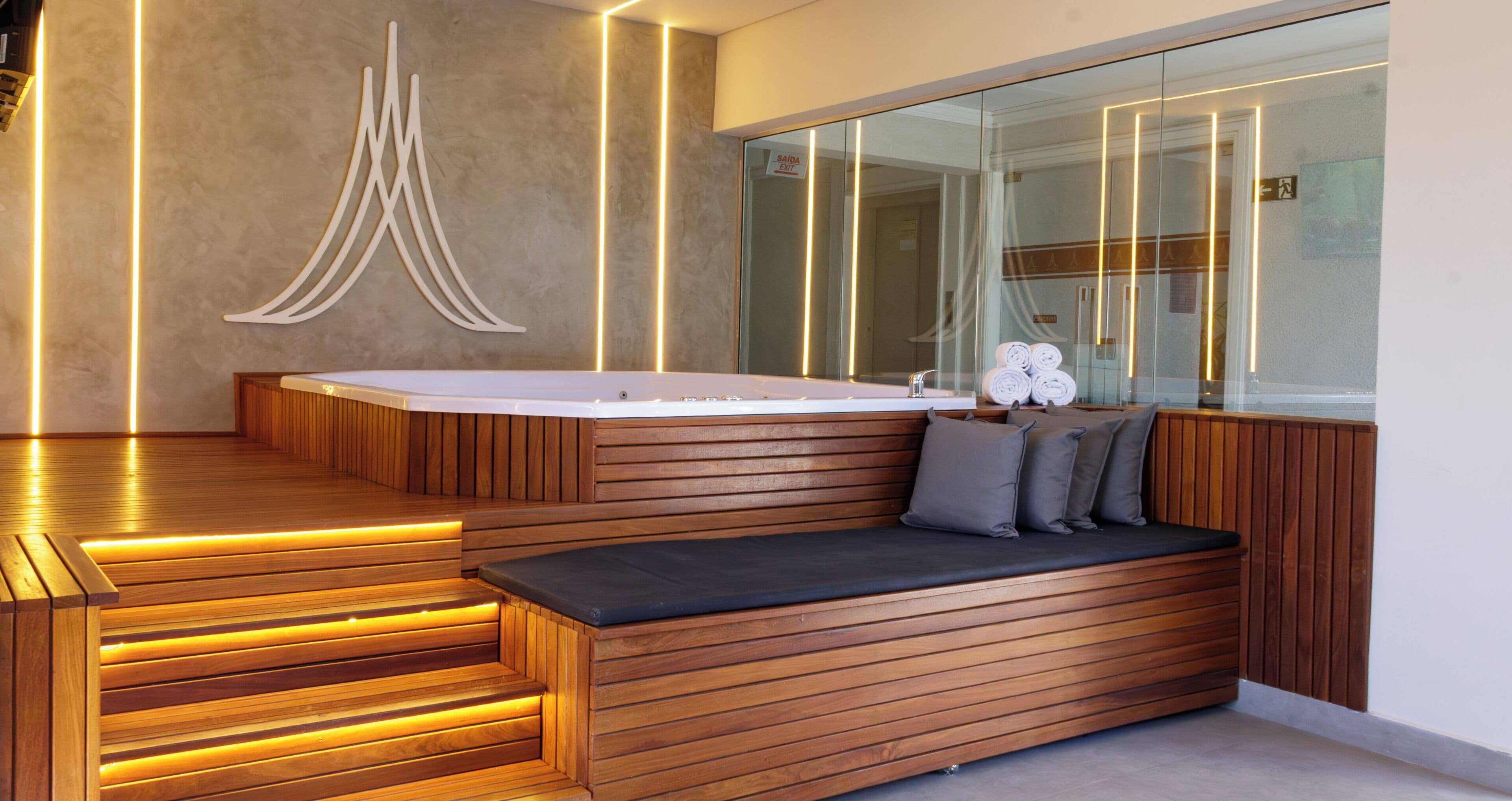 Un bagno moderno con una panca in legno, uno specchio grande e una vasca idromassaggio.