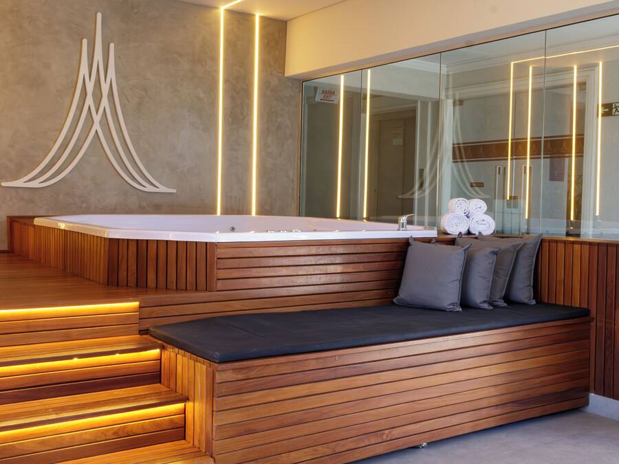 Un bagno moderno con una panca in legno, uno specchio grande e una vasca idromassaggio.