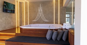 A modern bathroom with a freestanding bathtub, wooden seating, and a wall-mounted artwork. - Marsala Apart Hotel (Mogi das Cruzes)
