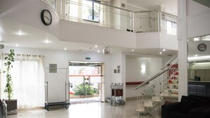 A spacious lobby with a staircase, a reception desk, and a plant. - Marsala Apart Hotel (Mogi das Cruzes)