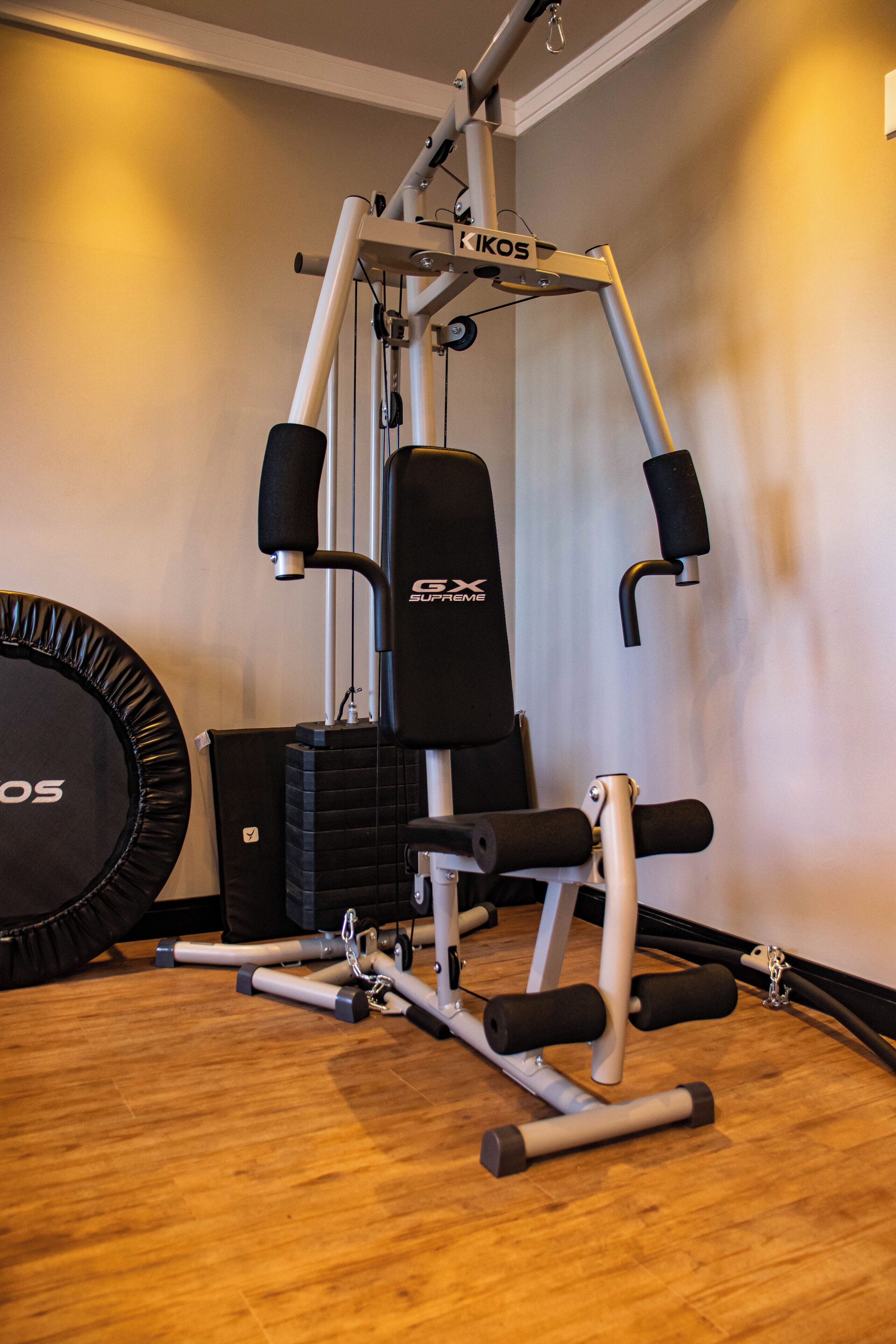 Uma academia com uma máquina Kikos, um banco e um grande rolo de exercícios.