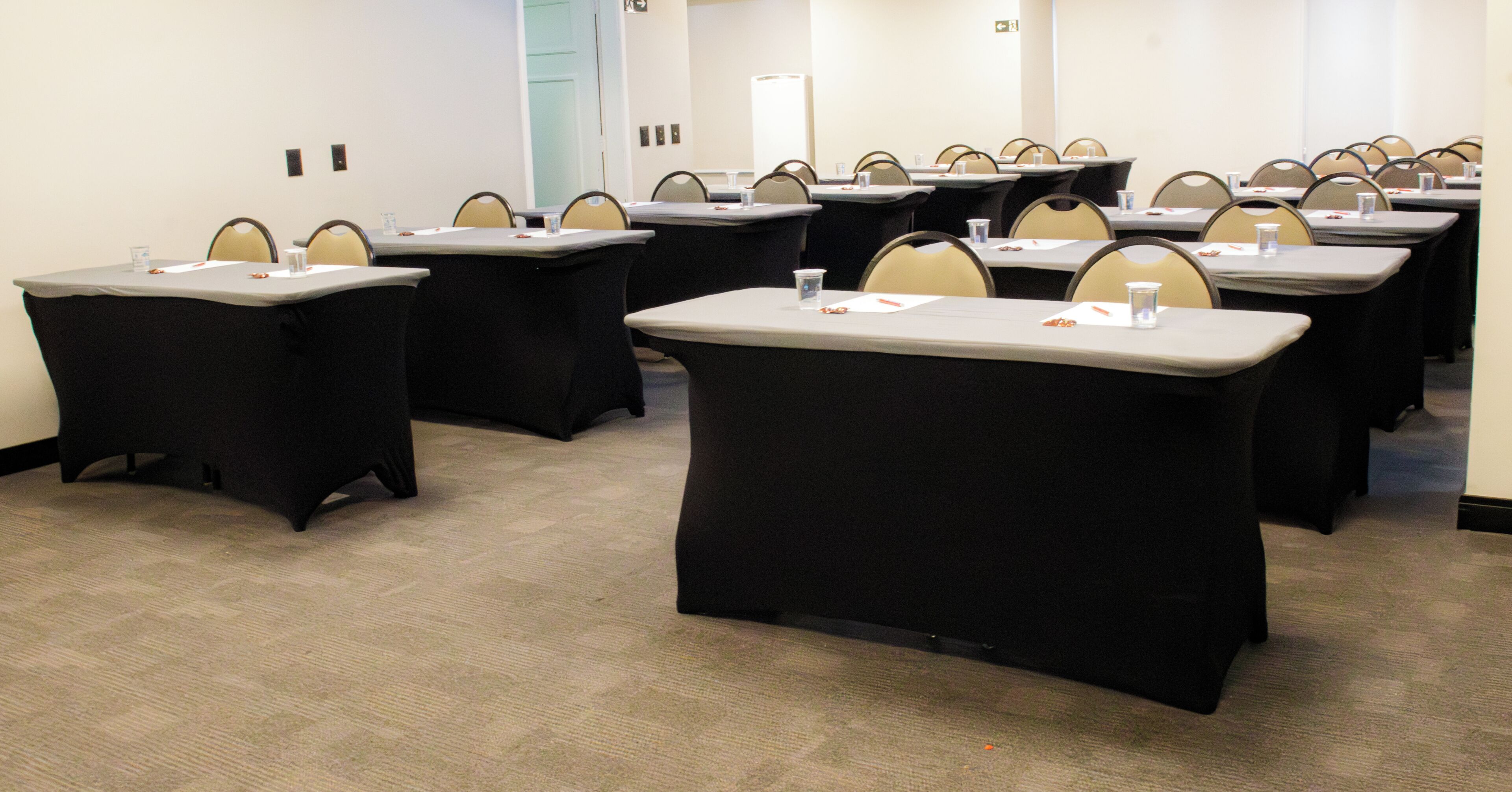 A conference room with multiple tables, chairs, and a carpeted floor.