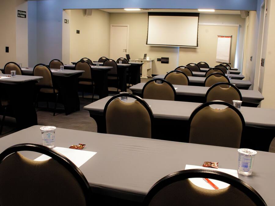 A conference room with tables, chairs, a projector screen, and a whiteboard.