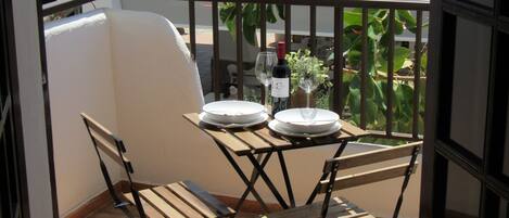 A balcony with a table and chairs, a bottle of wine, and a potted plant.