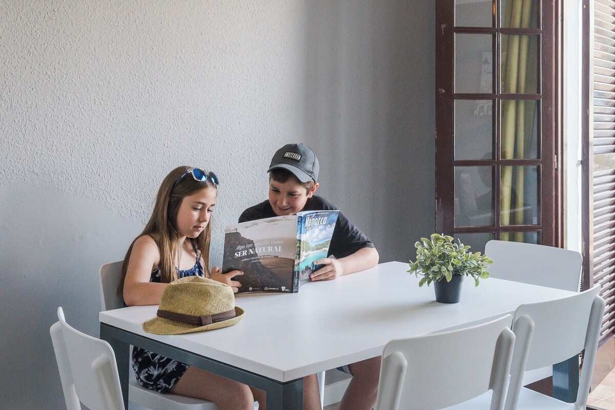 Dos personas sentadas en una mesa blanca con una planta en maceta.