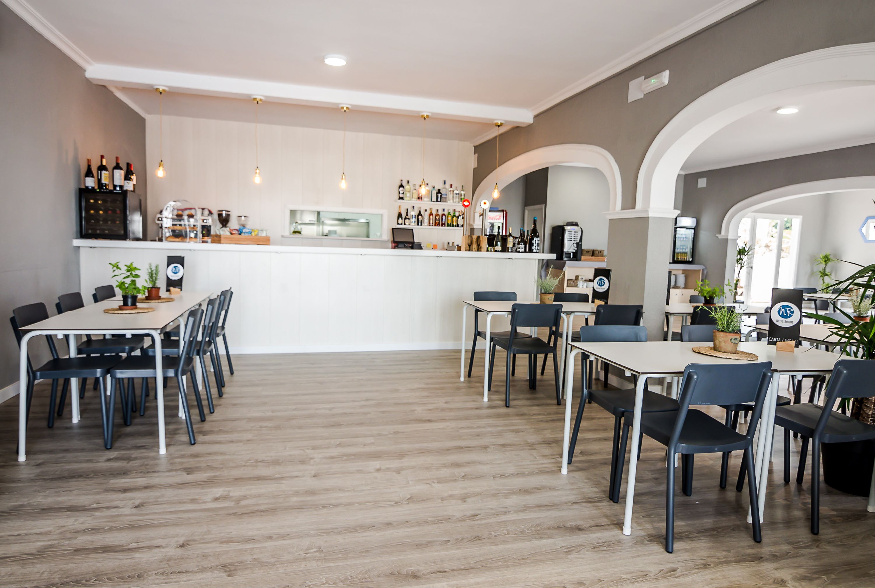 Ein moderner Essbereich mit Bar, Holzboden und schwarzen Stühlen.