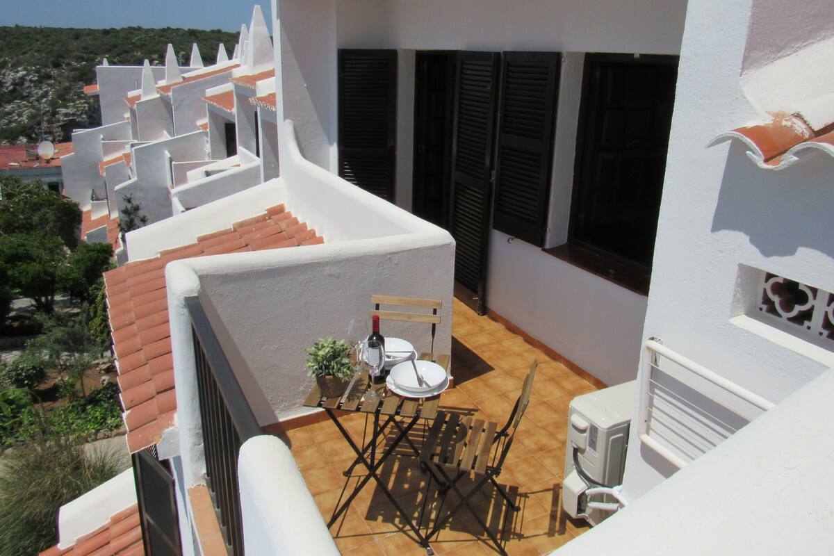 Ein Balkon mit Tisch, Stühlen und einer Topfpflanze.