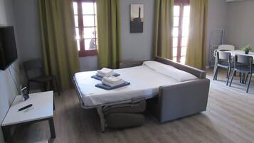 Una habitación de hotel con cama, escritorio, silla, mesa y televisor.