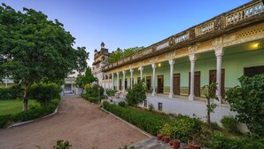 A historic building with a covered walkway, columns, and potted plants. - Neemrana's - Piramal Haveli (Jhunjhunu)