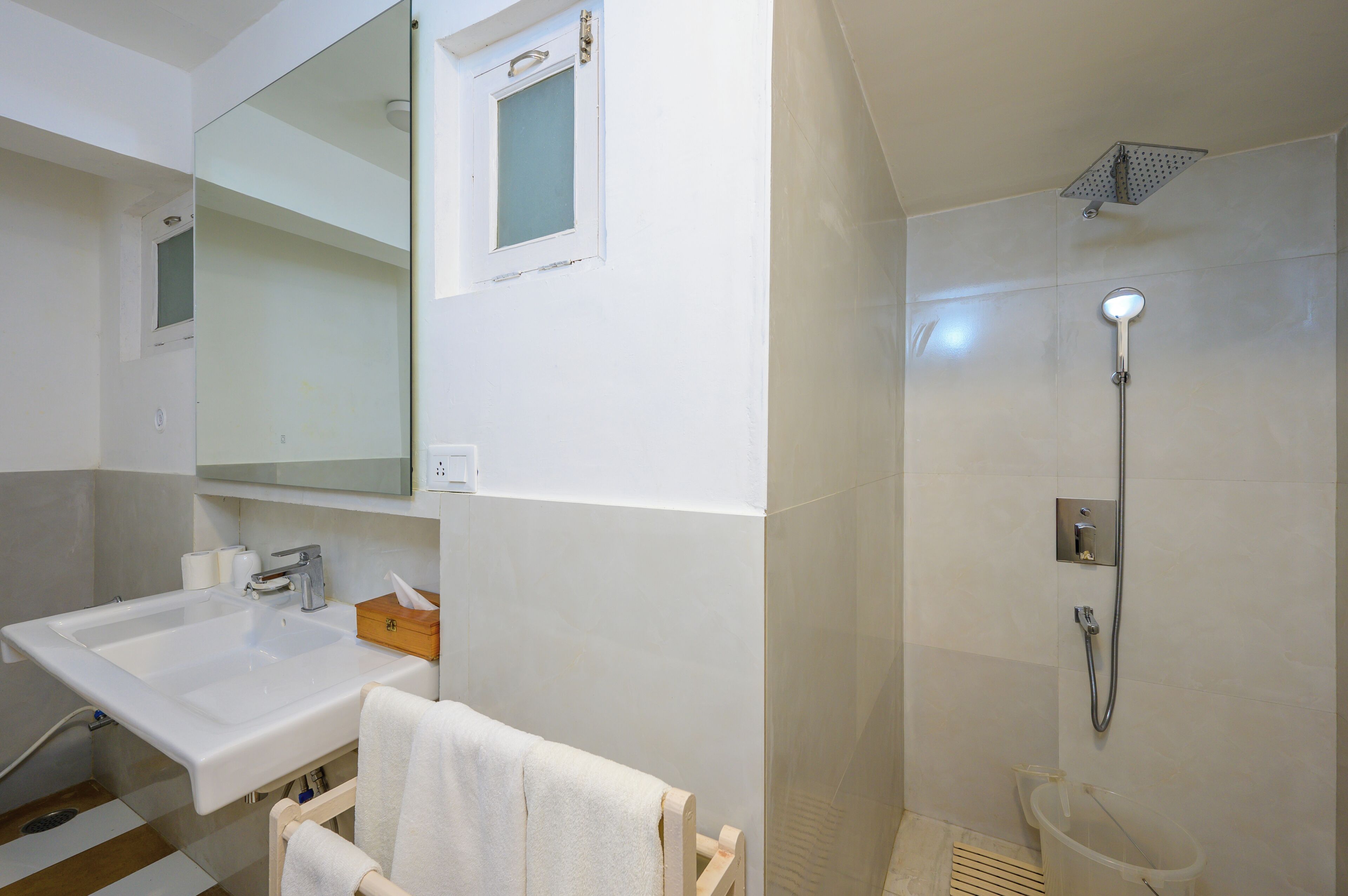 A bathroom with a sink, mirror, shower, and towel rack.