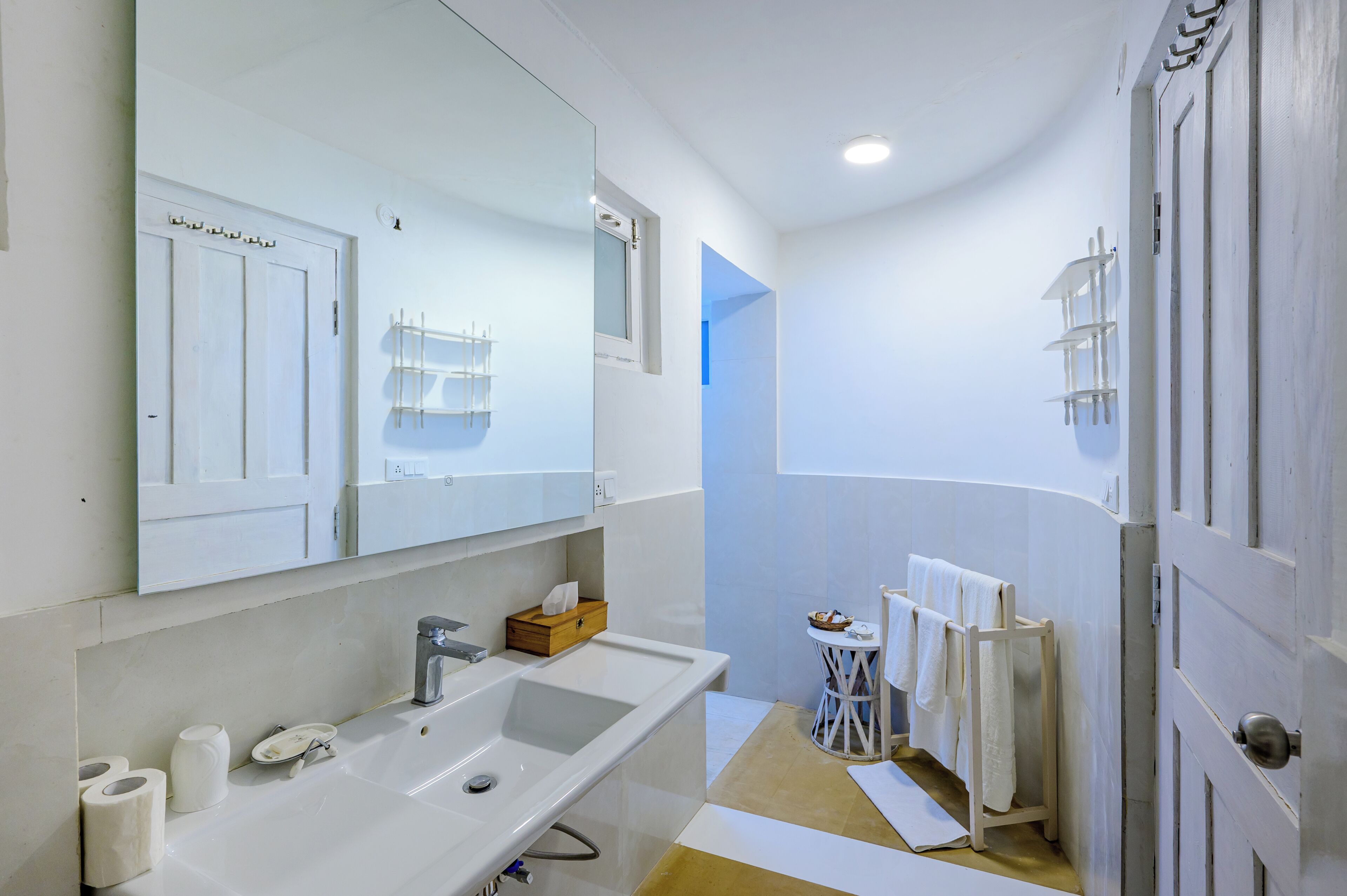 A bathroom with a large mirror, a sink, a toilet, and a towel rack.