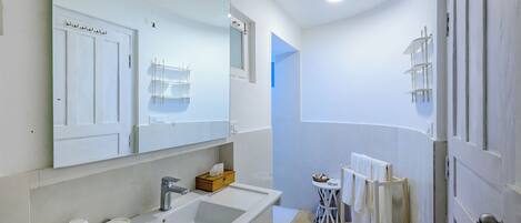A bathroom with a large mirror, a sink, a toilet, and a towel rack.