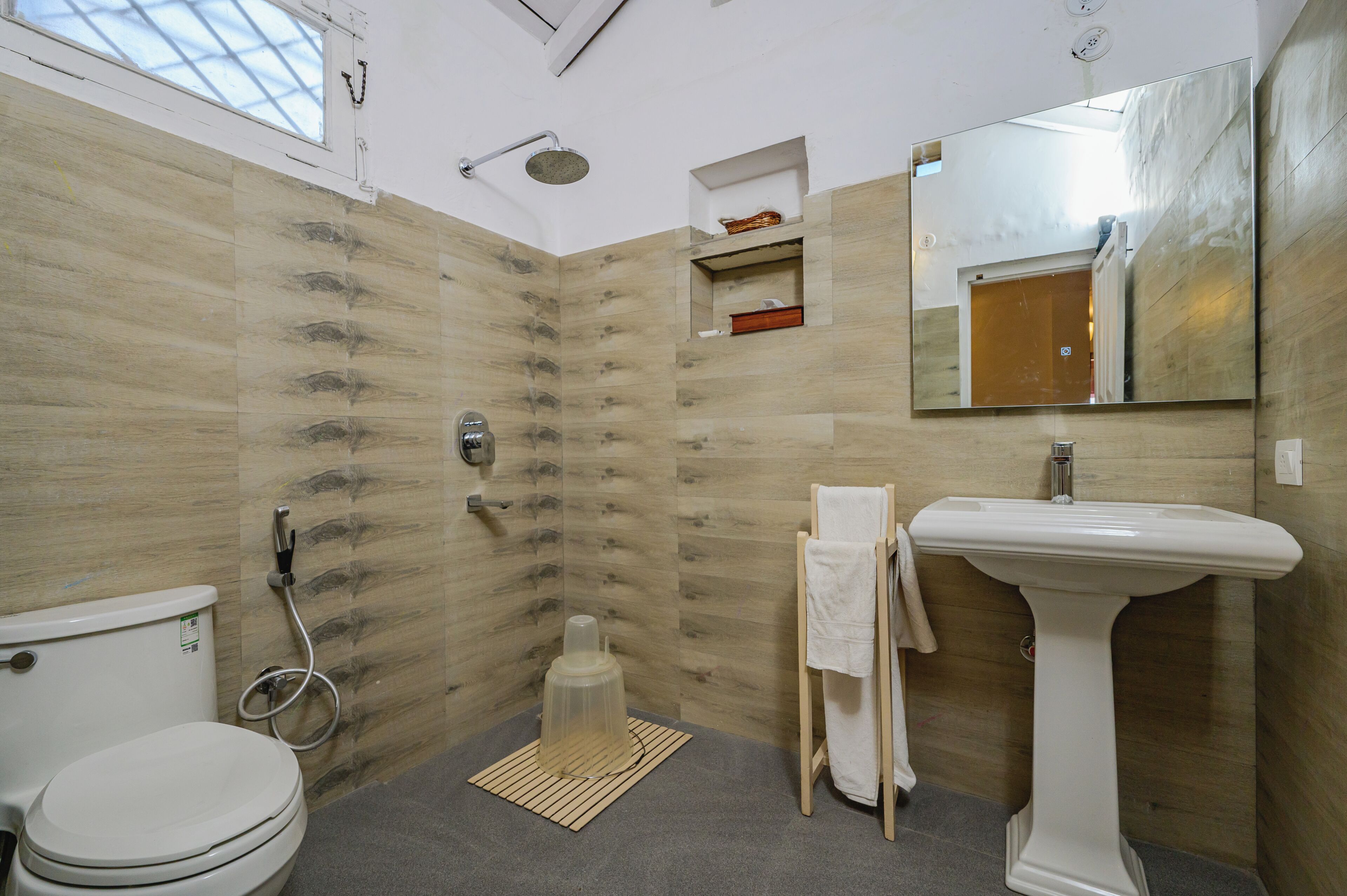 A bathroom with a toilet, shower, sink, and mirror.