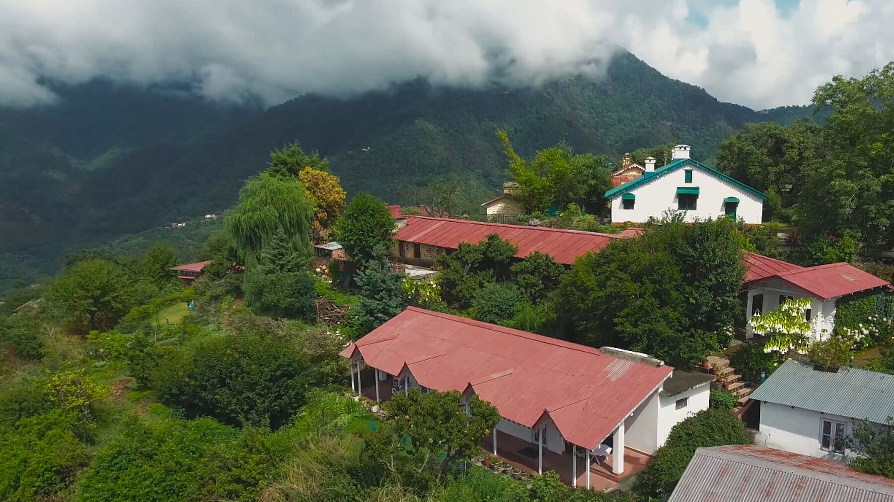 Un ensemble de maisons traditionnelles aux toits rouges, nichées au cœur d’une région montagneuse et verdoyante.