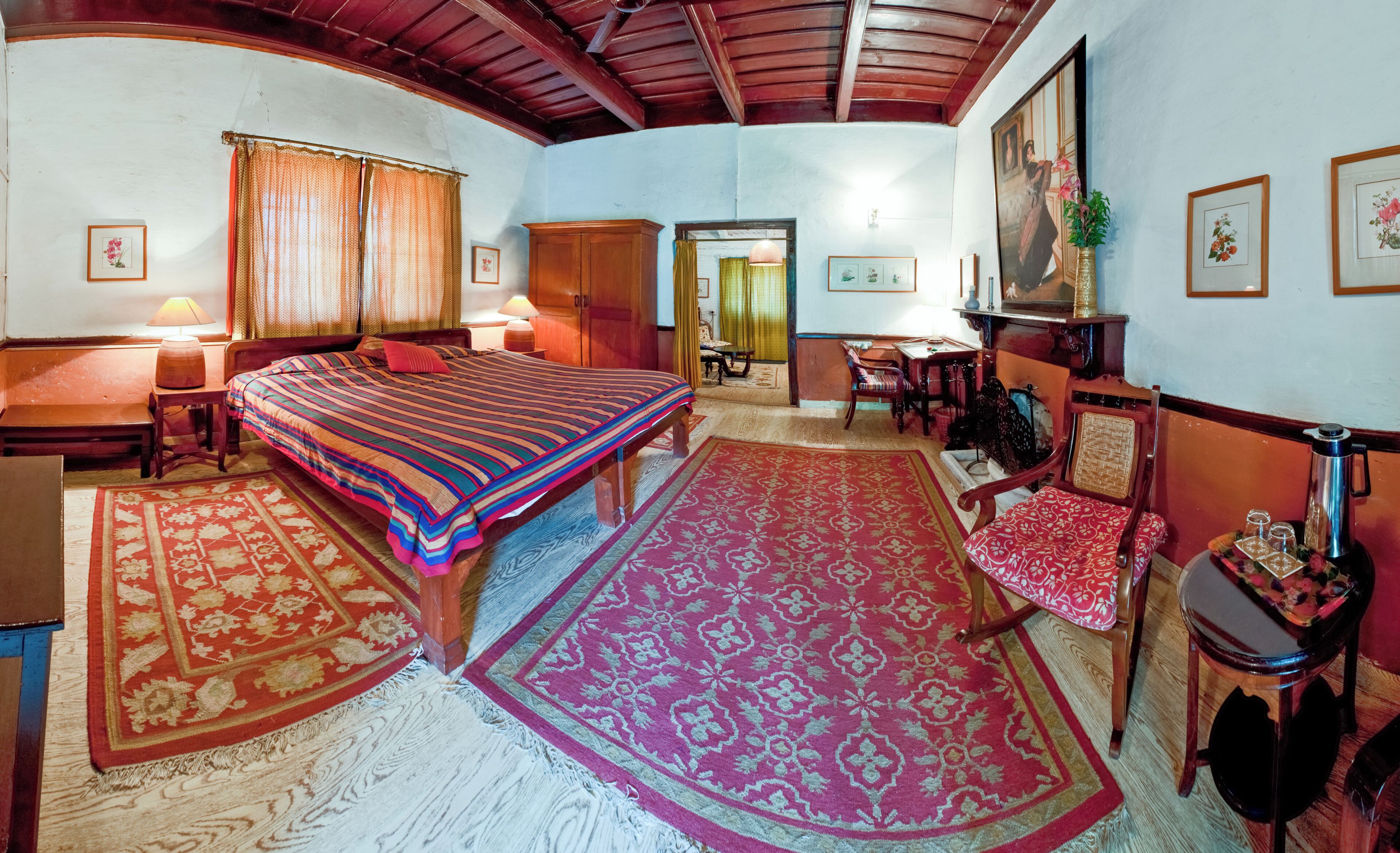 Une chambre traditionnelle avec un lit, deux tapis, une armoire en bois, une table et une chaise.