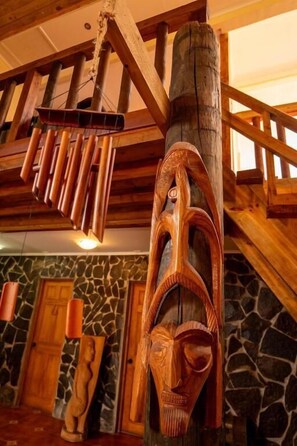 A wooden interior with a stone wall and a wooden ceiling structure. - Hotel Uka Mana (Hanga Roa)