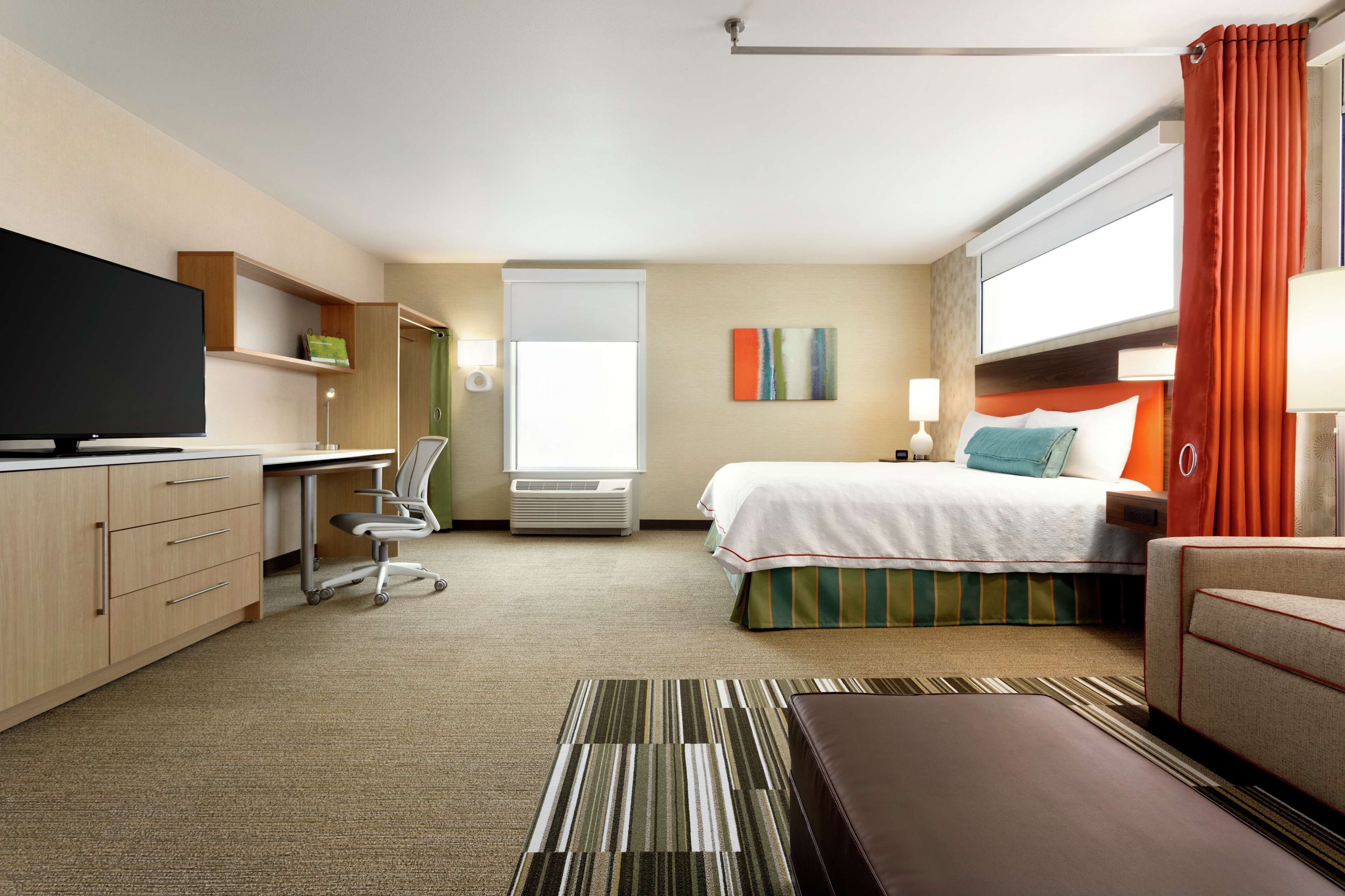 Une chambre d’hôtel équipée d’un lit, d’un bureau, d’une chaise, d’une télévision et d’une fenêtre avec des rideaux.