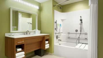 A modern bathroom with a wooden vanity, a large mirror, a bathtub, and a shower.