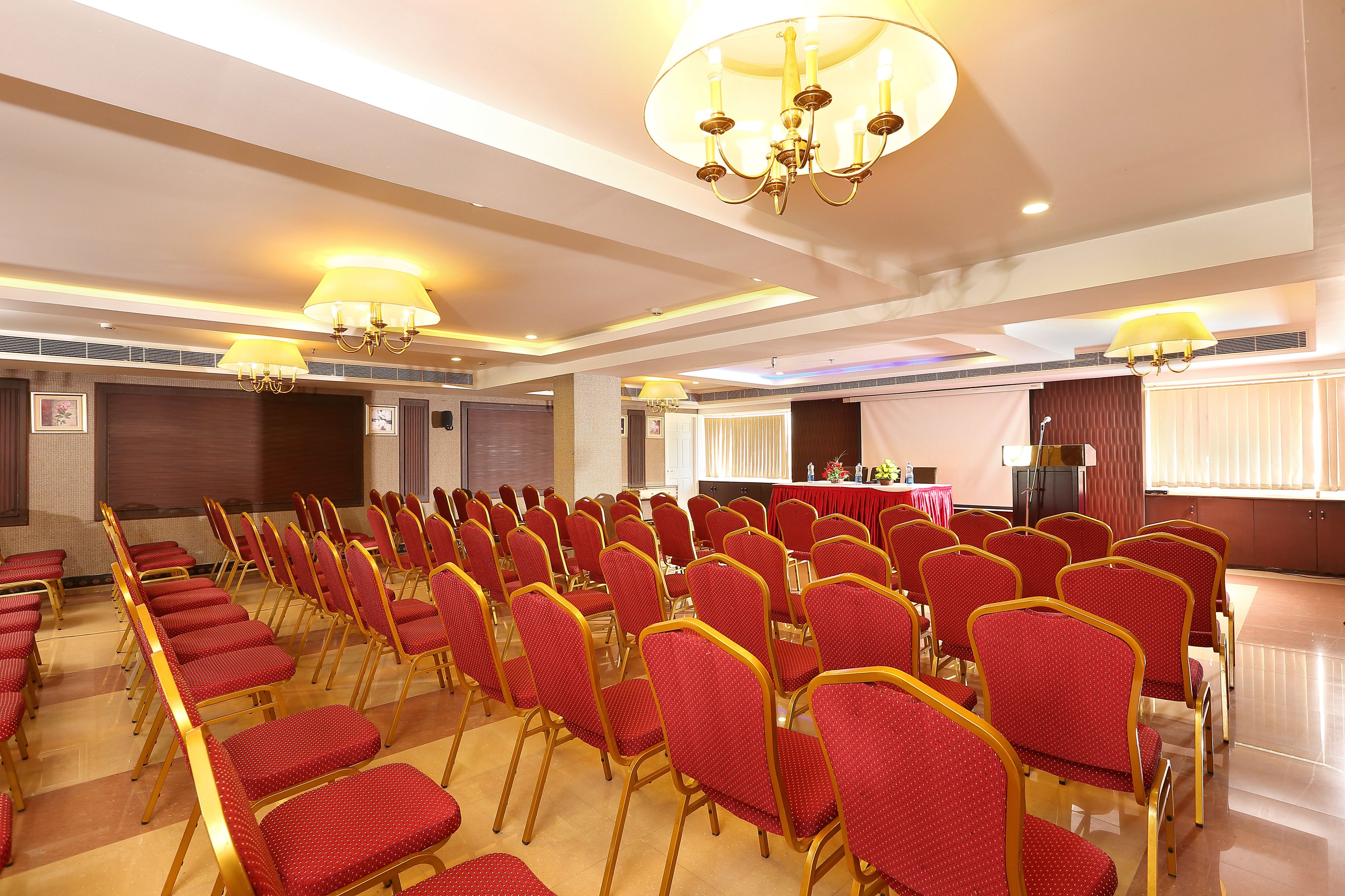 A conference room with rows of red chairs and a stage area.
