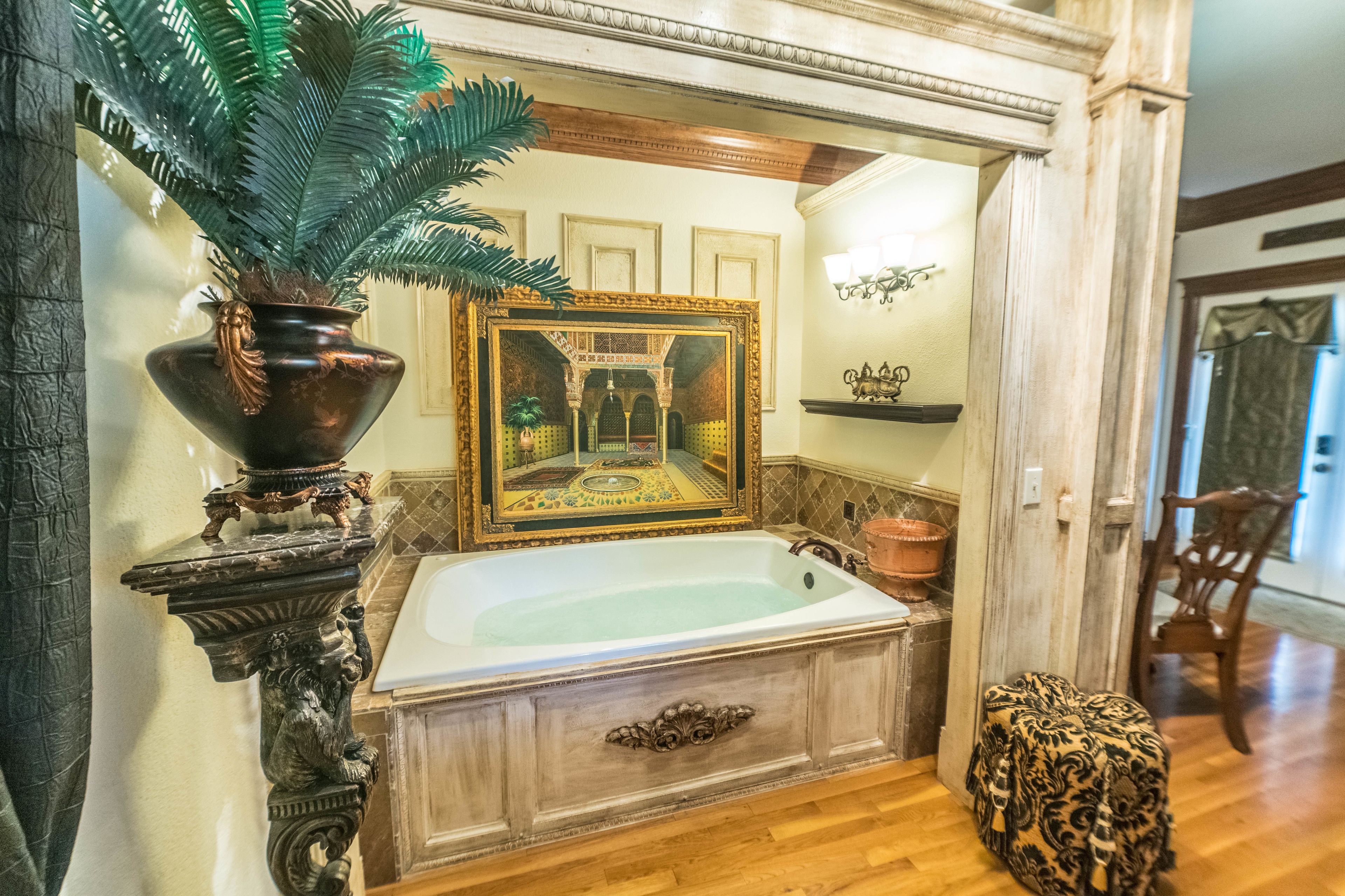 Une salle de bain avec une grande baignoire, un miroir décoratif et une plante en pot.