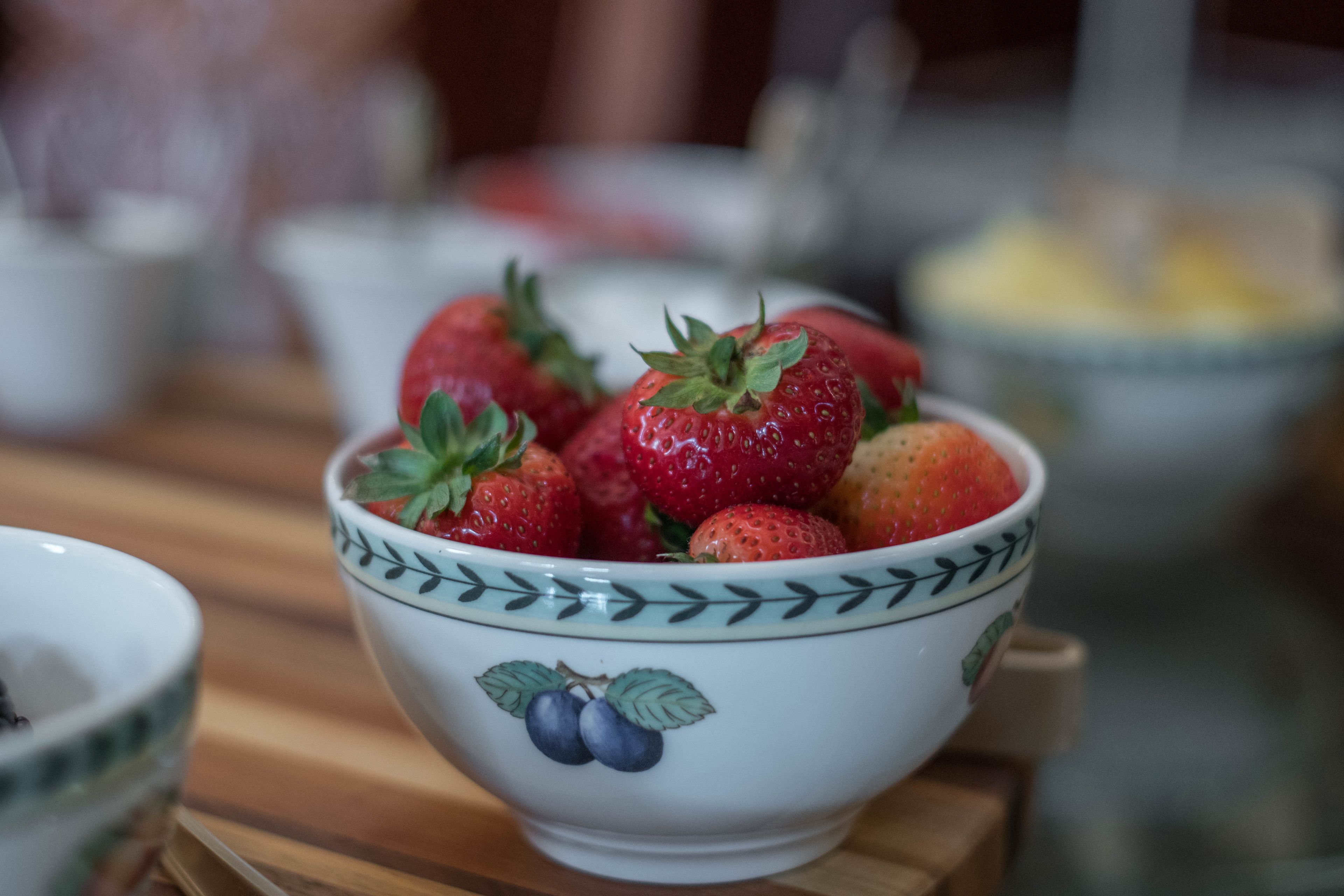 Un tazón de fresas sobre una mesa de madera.