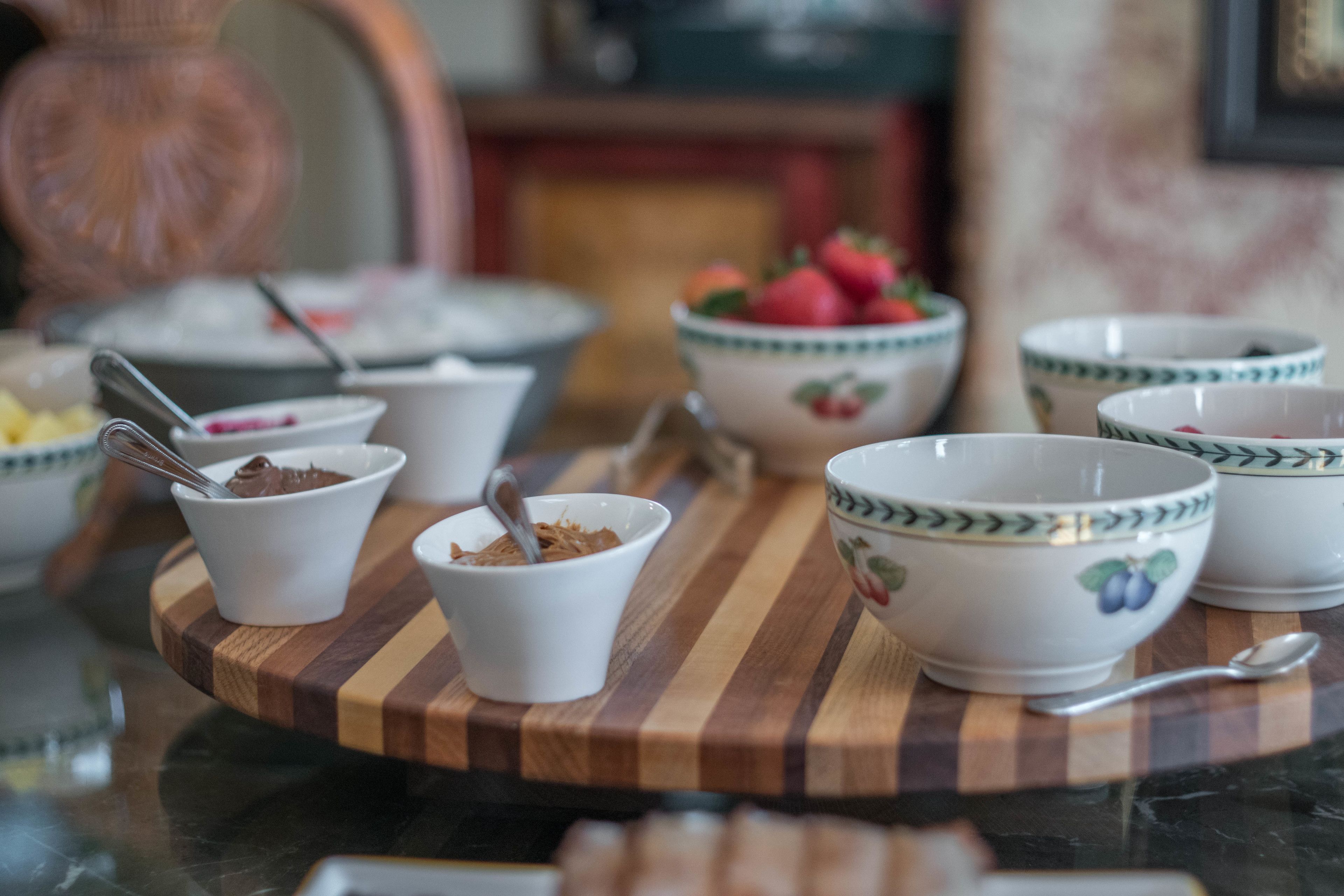 Une planche de service en bois avec des bols contenant des aliments et des cuillères.