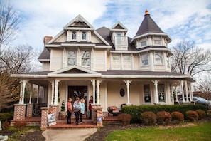 A large, two-story house with a wrap-around porch, a turret, and a chimney. - The Victoria B & B (Bentonville)