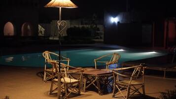 Un espace aménagé au bord de la piscine, avec des meubles en osier et une table, le tout entouré par la piscine.