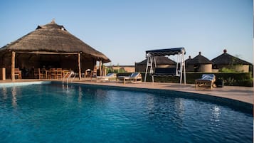 Una piscina al aire libre, sillones reclinables de piscina