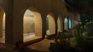 A series of arched structures with a warm, illuminated interior, suggesting a tranquil and inviting atmosphere. - Le Grand Calao (Ouagadougou)