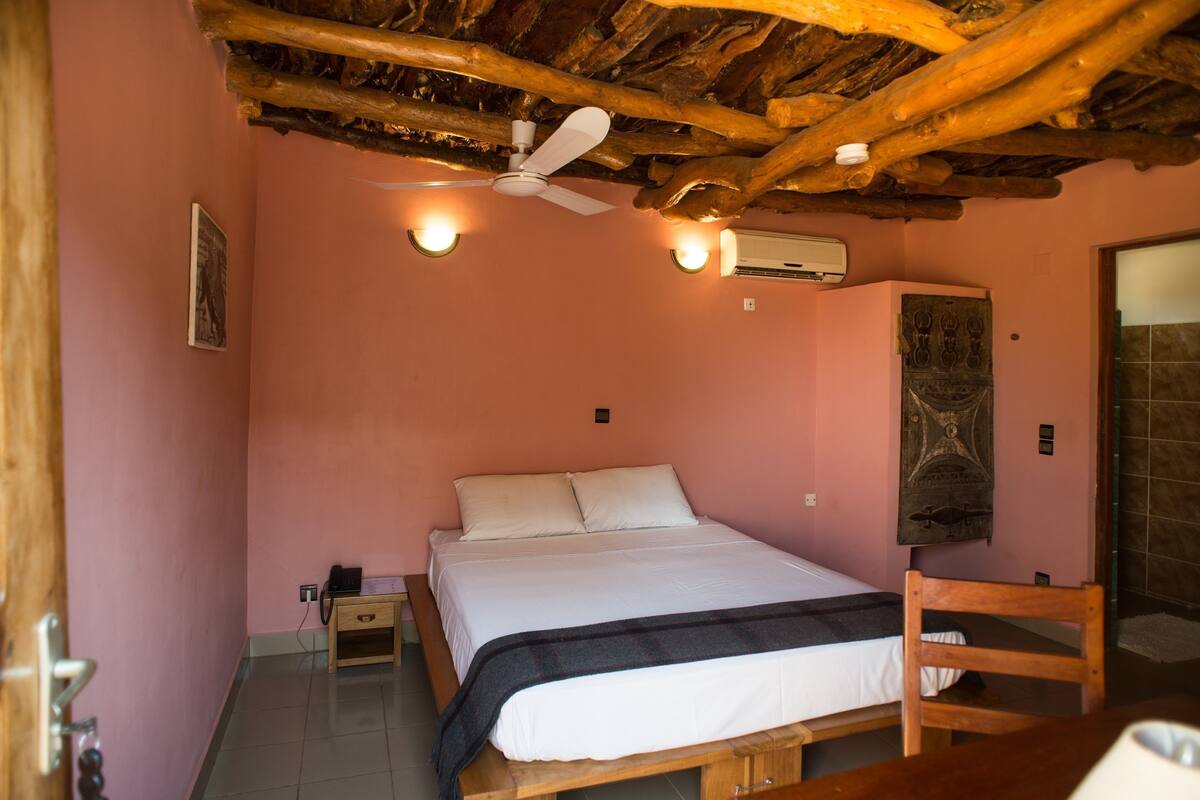 A bedroom with a wooden bed, a ceiling fan, and an air conditioning unit.