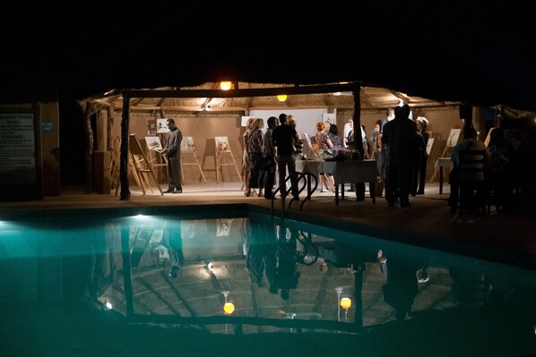 An indoor pool area with a covered seating area and a group of people gathered around a table.