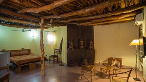 A rustic room with a wooden ceiling, a bed, a desk, and a chair. - Le Grand Calao (Ouagadougou)