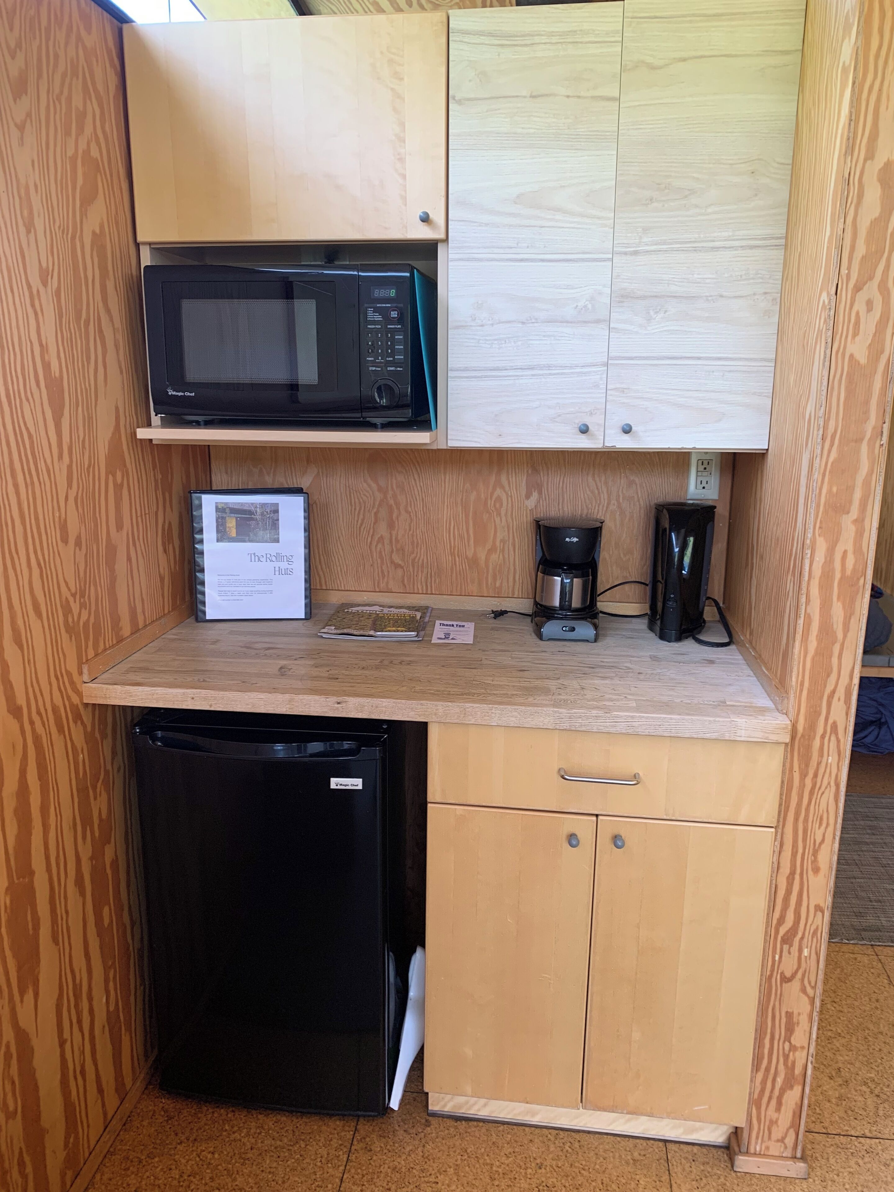 A compact kitchenette with a microwave, coffee maker, and a small refrigerator.