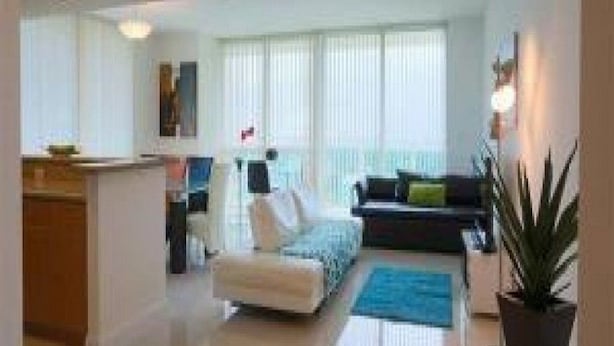 A modern living room with a sofa, armchair, and a dining area with a table and chairs. - Miami Luxury Suite in Downtown Brickell (Miami)