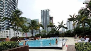 A swimming pool surrounded by palm trees and high-rise buildings. - Miami Luxury Suite in Downtown Brickell (Miami)