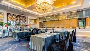 A banquet hall with tables set for a formal event, a large chandelier, and a decorative wall with a geometric pattern. - Beijing Jizhong Taurus Hotel (Beijing)