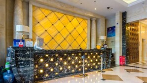 A hotel reception area with a marble counter, a large yellow patterned wall, and a modern chandelier. - Beijing Jizhong Taurus Hotel (Beijing)