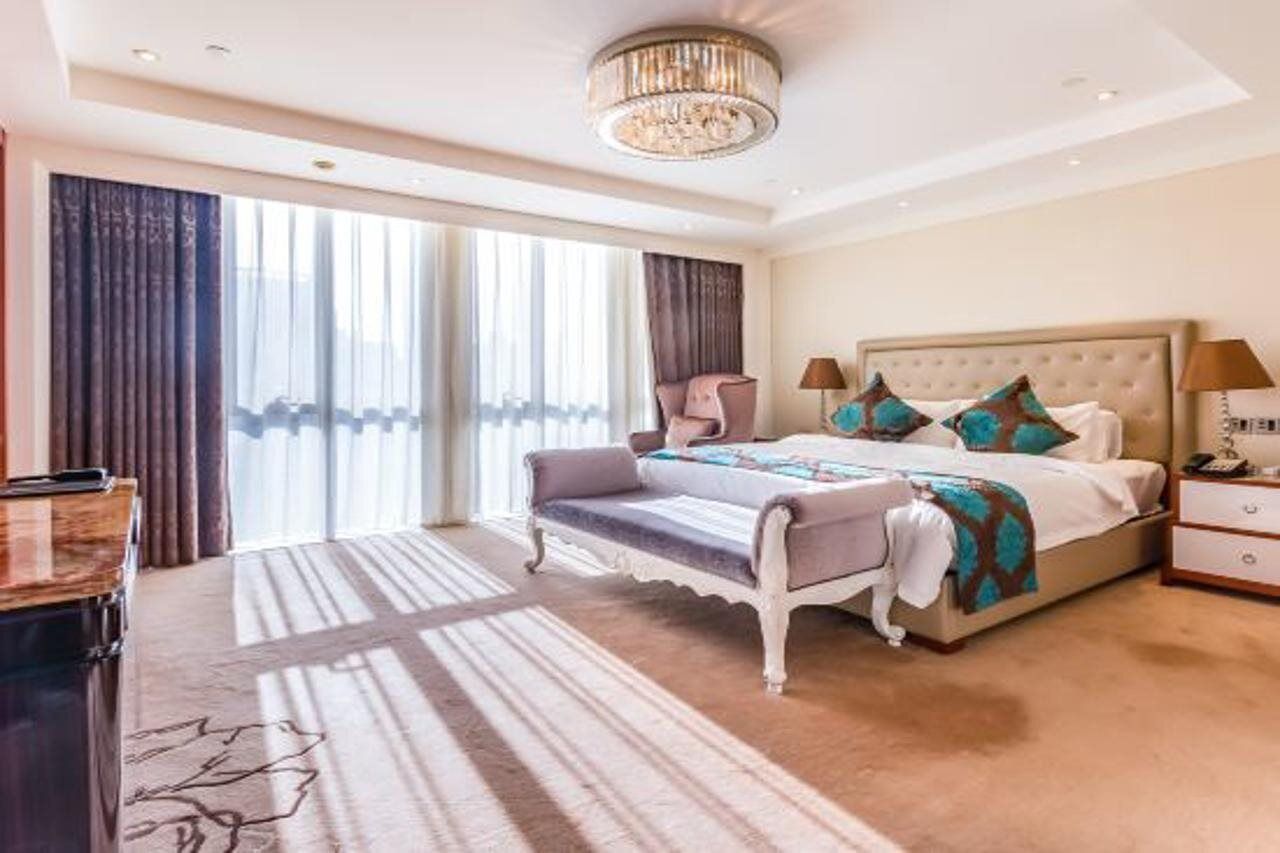 Un dormitorio amplio con una cama grande, un sillón y una mesita de noche.