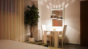 A hotel room with a bed, a dining table with chairs, a potted plant, and a mirror with pendant lights. - Malaga Apartments Andes (Málaga)