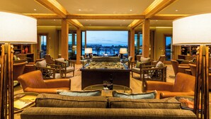 Un amplio salón con una isla central, asientos cómodos y grandes ventanales que ofrecen vistas de la ciudad.