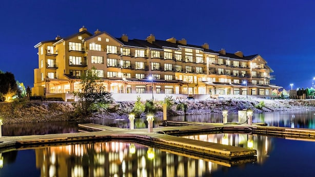Un hotel de varios pisos con una piscina reflectante al frente.