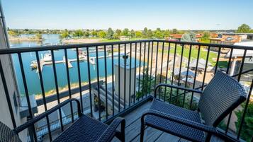A balcony with wicker furniture overlooking a marina and a swimming pool.