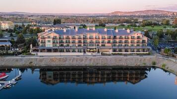 Un hôtel à plusieurs étages avec une piscine dont la surface réfléchit la lumière, située à l’avant.