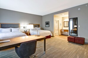 A hotel room with two beds, a desk, a chair, a mirror, and a small seating area. - Hampton Inn & Suites by Hilton Grande Prairie (Grande Prairie)
