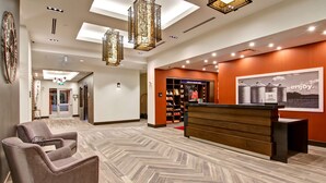 A hotel lobby with a reception desk, a seating area, and a wall with a poster.