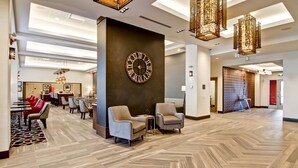 A spacious lobby with a large wall clock, modern furniture, and a herringbone wood floor.