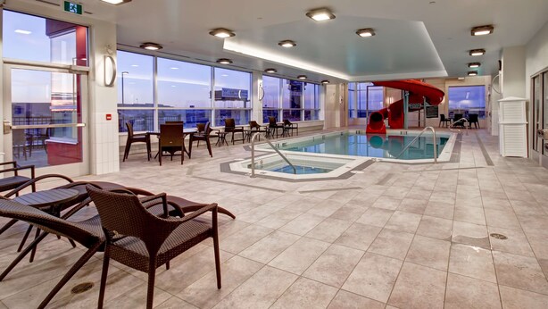A pool area with chairs and a hot tub.