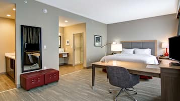 A hotel room with a bed, desk, chair, and a mirror.